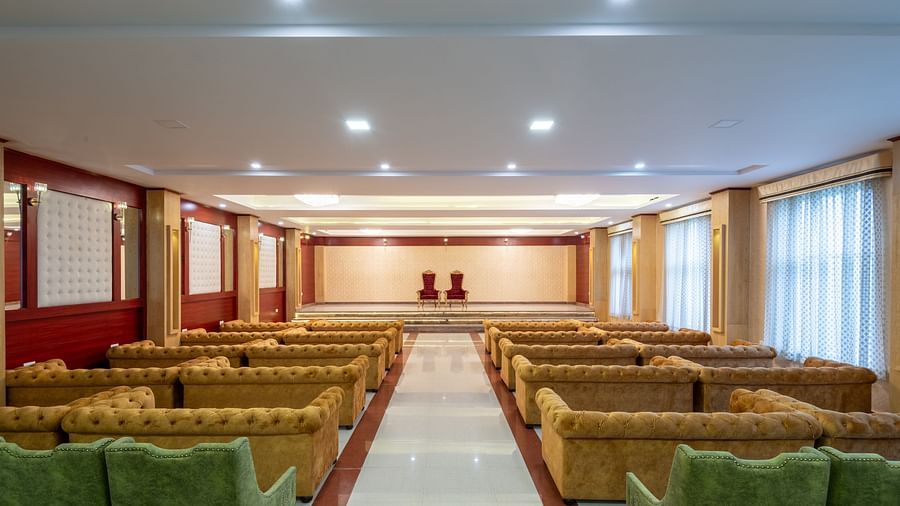 A over the shoulder shot of an expansive banquet hall with brown and green sofas at DLS Tehri Resort and Spa.